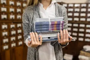 Office digitisation: Hands move old paper archives into a modern scanner to maximise efficiency and smarter business planning.