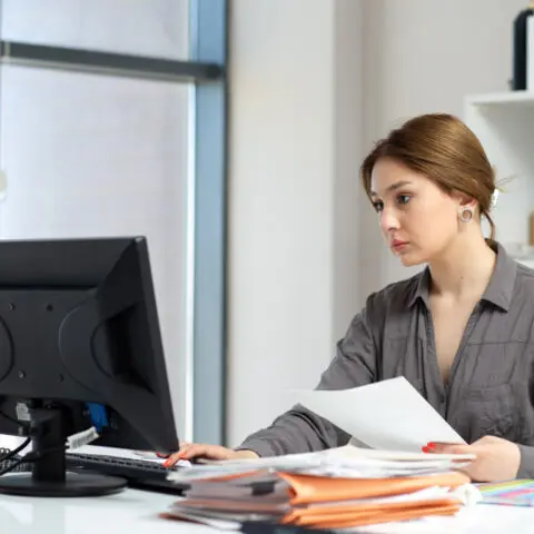 A focused office manager reviewing financial reports on a digital tablet to identify managed print service cost savings.