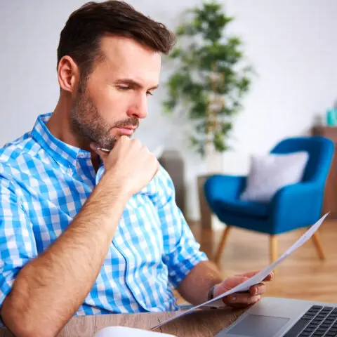 A business owner reviews office expenses on a digital tablet to understand photocopier per click charges.