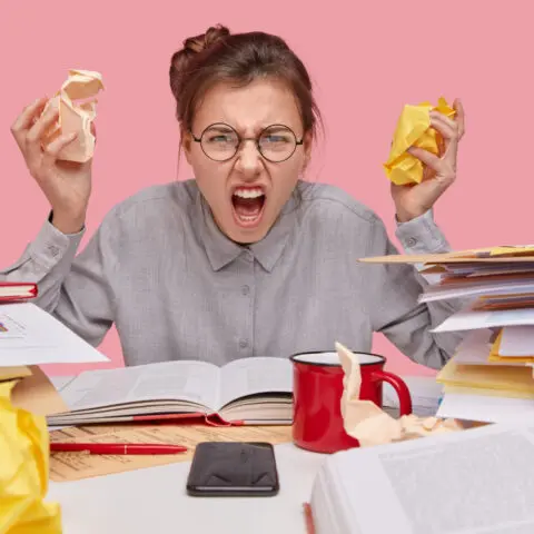 A stressed office worker reviews a stack of multiple invoices to find the benefits of managed print services consolidated billing.