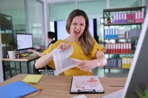 A frustrated business owner reviews office bills, comparing commercial printer vs cheap office printer cost.