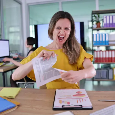 A frustrated business owner reviews office bills, comparing commercial printer vs cheap office printer cost.