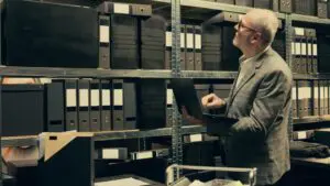 Filing cabinet being replaced by a digital workstation with AI to show digital document management benefits.