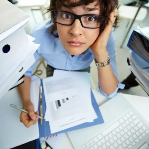 Stressed business owner with paper files by a laptop before the digital compliance deadline Lancashire.
