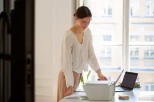 A person using a high-end scanner at a minimalist modern office desk to implement clear desk policy scanning solutions.
