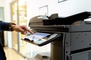 Person reviews Copier Features Checklist next to copier, highlighting key features to maximise buying decisions.