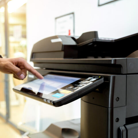 Person reviews Copier Features Checklist next to copier, highlighting key features to maximise buying decisions.