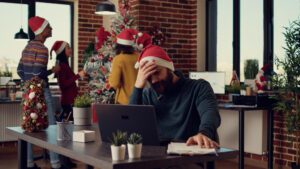 Stressed employee hiding behind a plant at a Christmas party, highlighting Office Party Anxiety Survival Guide.
