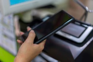 Hands printing from a smartphone using a multifunction printer's touchscreen, demonstrating effective Mobile Devices Copier Integration to maximise efficiency.
