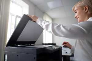 Professional woman operating an MFP with money visible, highlighting Multi-Function Printers Cost Savings to maximise office budget.