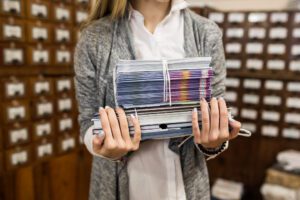 Office digitisation: Hands move old paper archives into a modern scanner to maximise efficiency and smarter business planning.