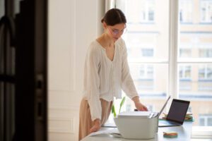 A person using a high-end scanner at a minimalist modern office desk to implement clear desk policy scanning solutions.