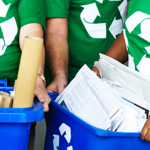 An office worker recycles paper documents in an eco-friendly workspace to support zero waste office printing UK.