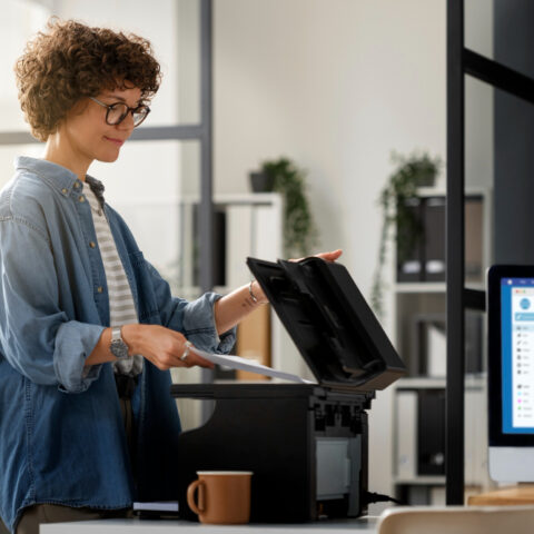 A stressed professional sitting at a desk with multiple computer screens displaying notifications.